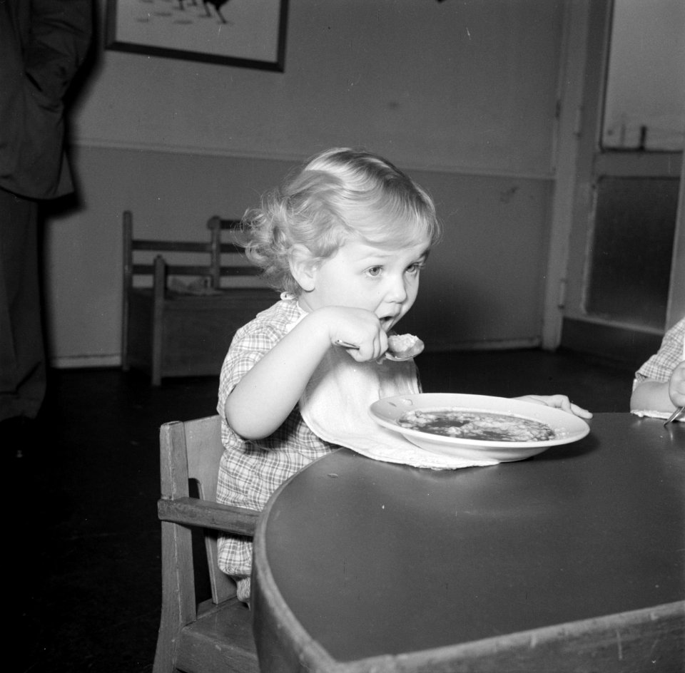 Kleuter zit aan een tafeltje te eten, Bestanddeelnr 252-9097