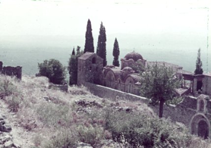 Kleurenfoto (verbleekt) van een kerk, muur en cypressen aan de kust, Bestanddeelnr 254-6538 photo