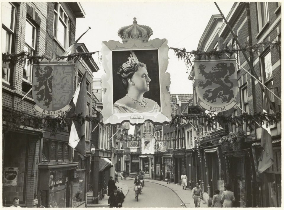 Kleine Houtstraat bij de hoek Helmbrekerssteeg ziende naar het zuiden. De straat is versierd ter gelegenheid van het 50-jarig regerings jubileum van Koningin Wilhelmina. NL-HlmNHA 54010653