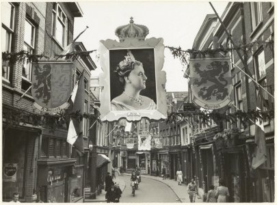 Kleine Houtstraat bij de hoek Helmbrekerssteeg ziende naar het zuiden. De straat is versierd ter gelegenheid van het 50-jarig regerings jubileum van Koningin Wilhelmina. NL-HlmNHA 54010653