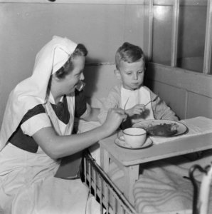 Kleuter eet zelfstandig Naast hem een verpleegster, Bestanddeelnr 900-7972