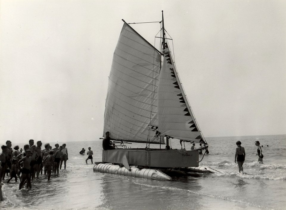 Klaas de Voogt, een blinde man uit Zandvoort, aan het strand met een door hem op het gevoel gebouwde zeilboot. (Catamaran) Aangekocht in 1977 van fotograaf C. de Boer. Identificatienummer 54, NL-HlmNHA 1478 25900 K 38