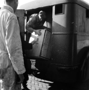 Kisten worden uit een vrachtwagen gehaald op de Oude Turfmarkt te Amsterdam, Bestanddeelnr 900-8699