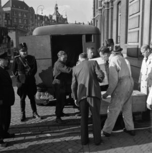 Kisten worden uit een vrachtwagen gehaald voor de ingang van het gebouw van de N, Bestanddeelnr 900-8695