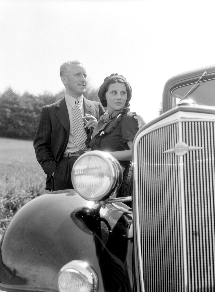 KLM vertegenwoordiger Harry Laponder met zijn schoonzus staande achter een Chevr, Bestanddeelnr 190-0256