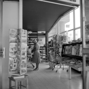 Klanten kijken rond in een boekwinkel, er staat ook een kaartenrek en er liggen , Bestanddeelnr 255-1852