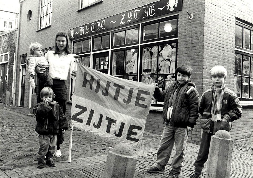 Kinderkleding 'Hijtje - Zijtje'. Marie José van Offeren voor haar winkel aan de Korte Bogaardstraat hoek Lange Bogaardstraat. Aangekocht in 1984 van fotograaf C. de Boer. - Gepubliceerd in h, NL-HlmNHA 54014423