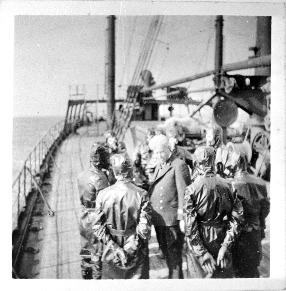 Kapitein op het dek van een schip met bemanningsleden in beschermende pakken te, Bestanddeelnr 935-3189