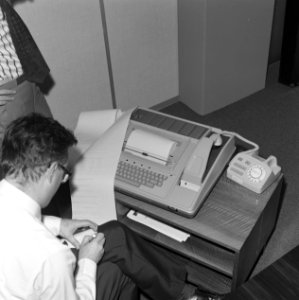 Kantooremployé bedient eenteletypewriter fax van Texas Instruments, Bestanddeelnr 167-1017