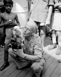 Kaketoe op de filmcamera van een oorlogscorrespondent. Naast hem een Indonesisc…, Bestanddeelnr 10269