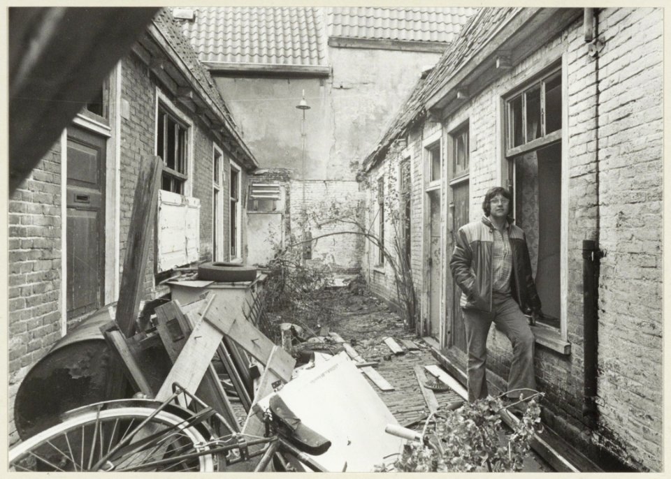 Karl Svoboda in de Koopallepoort. Karl heeft bakken vuil uit de steeg gehaald, maar de rotzooi blijft komen. NL-HlmNHA 54005082