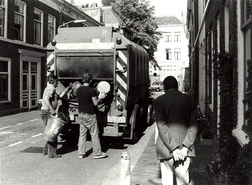 Korte Herenstraat z.n.h. westen. Het ophalen van het huisvuil. Aangekocht in 1982 van United Photos de Boer bv. - Negatiefnummer 18167 k 7 A. - Gepubliceerd in het Haarlems Dagblad van 01.09.1981