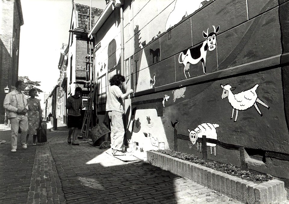 Korte Annastraat hoek Nieuwe Kerksplein, restauratie muurschildering door Annet Philipsen en Dieten Nijdam. Aangekocht in 1988 van United Photos de Boer bv. - Negatiefnummer 27974 K 6 A. - Gepubliceer
