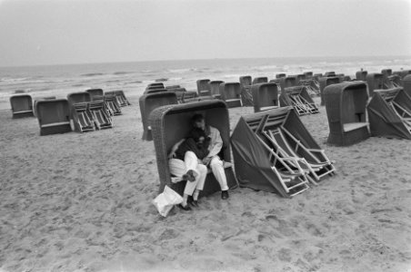 Koud en nat begin van de zomer twee wandelaars schuilen strandstoel, Bestanddeelnr 934-0167