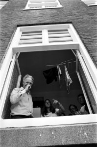 Kuijpers kijkt vanuit een raam van een woning, Bestanddeelnr 928-0761
