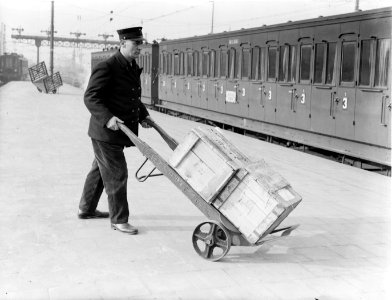 Kruier met kisten op het perron van het Centraal Station in Amsterdam, Bestanddeelnr 189-0177