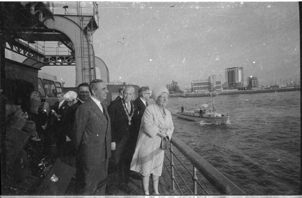 Koningin Juliana aan boord van een wagenveer, omringd door de burgemeester van Vlaardingen en Rotterdam, staatssecretaris van Verkeer en Waterstaat, M.J. Keyzer en mr. V.G.M. Marijnen van de Rijnmondraad