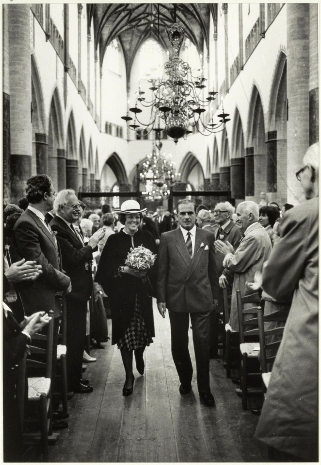 Koningin Beatrix betreedt de Grote of St. Bavokerk in gezelschap van president-kerkvoogd H. Vermaire i.v.m. de gerestaureerde kerk. Rechts op de foto o.a. de heren J.J. Fuykschot, J.J. Temmi, NL-HlmNHA 54015619