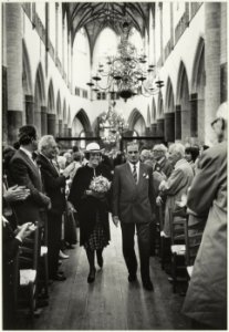 Koningin Beatrix betreedt de Grote of St. Bavokerk in gezelschap van president-kerkvoogd H. Vermaire i.v.m. de gerestaureerde kerk. Rechts op de foto o.a. de heren J.J. Fuykschot, J.J. Temmi, NL-HlmNHA 54015619