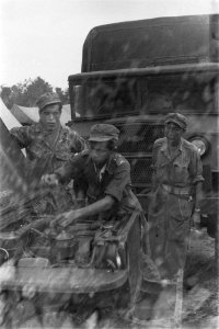 KNIL-militairen kijken onder een motorkap van een jeep, Bestanddeelnr 108-3-7