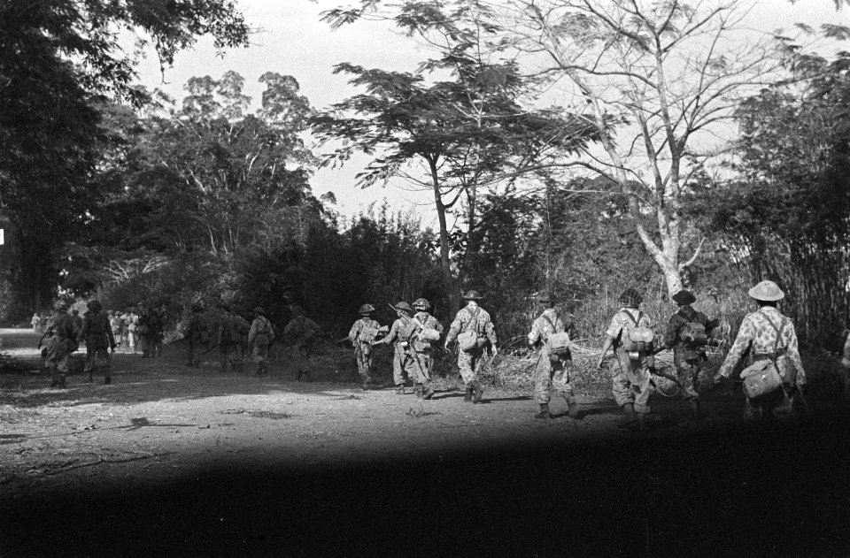 KNIL-militairen in camouflage-uniformen rukken op over een landweg., Bestanddeelnr 7431