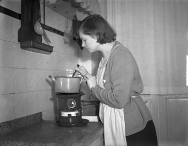 Koken op petroleum. Huisvrouw roert in pan, die staat op een petroleumstel, Bestanddeelnr 904-2882