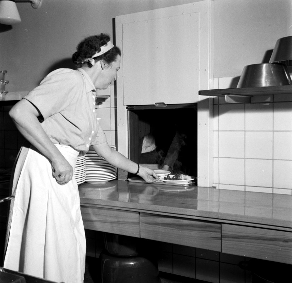 Kok met een dienblad met eten bij een doorgeefluik, Bestanddeelnr 252-8943