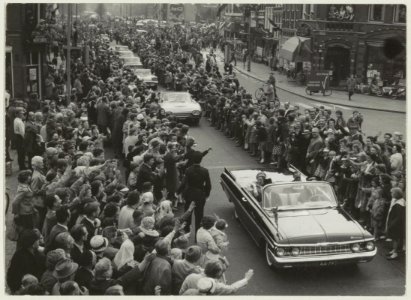 Koninklijk bezoek aan Haarlem. In de auto voorgrond Koningin Juliana en Prins Bernhard, daarachter de auto met de prinsessen op het Houtplein. NL-HlmNHA 54011215