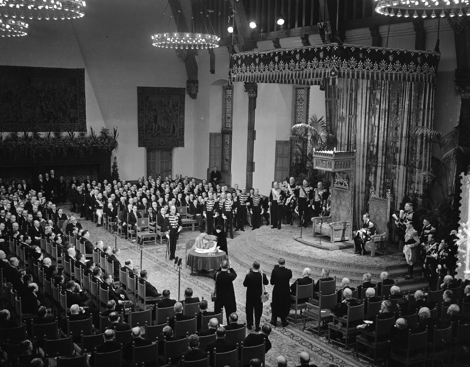 Koningin Juliana ondertekent de Acte van Bevestiging. Naast haar de Directeur va, Bestanddeelnr 906-8930