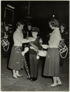 Leden van het Harmoniecorps en Bloemenmeisjes tijdens de Taptoe op de Grote Markt. NL-HlmNHA 54010529