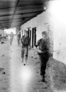 Leden van een patrouille lopen over de veranda van een groot gebouw, Bestanddeelnr 10728