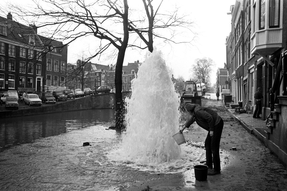 Lek in waterleiding Reguliersgracht Amsterdam, man met emmer bij opspuitend wate, Bestanddeelnr 925-1732