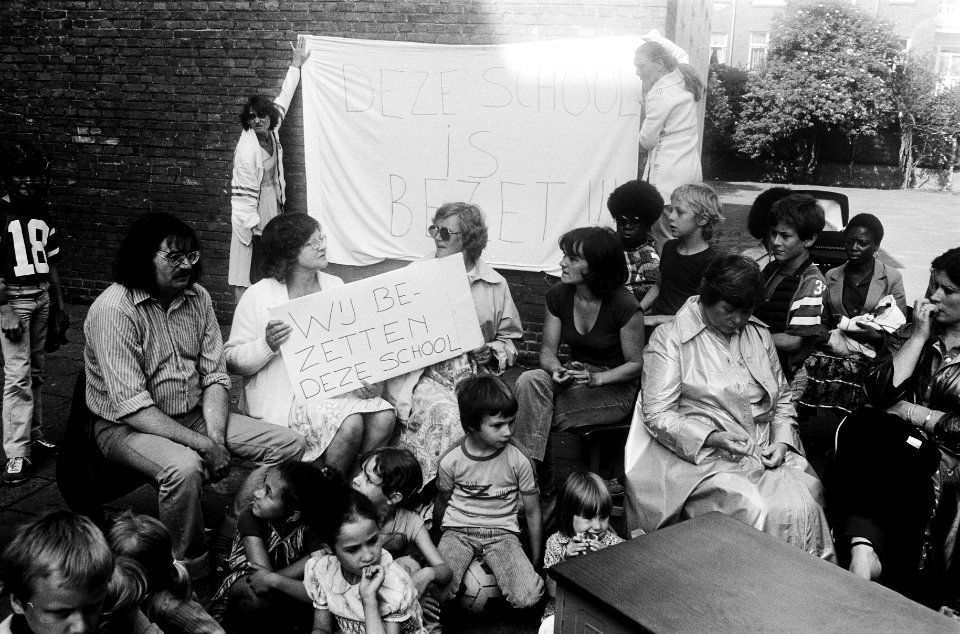 Leerkrachten zitten voor de school op een spandoek wij bezetten onze school, Bestanddeelnr 930-3344