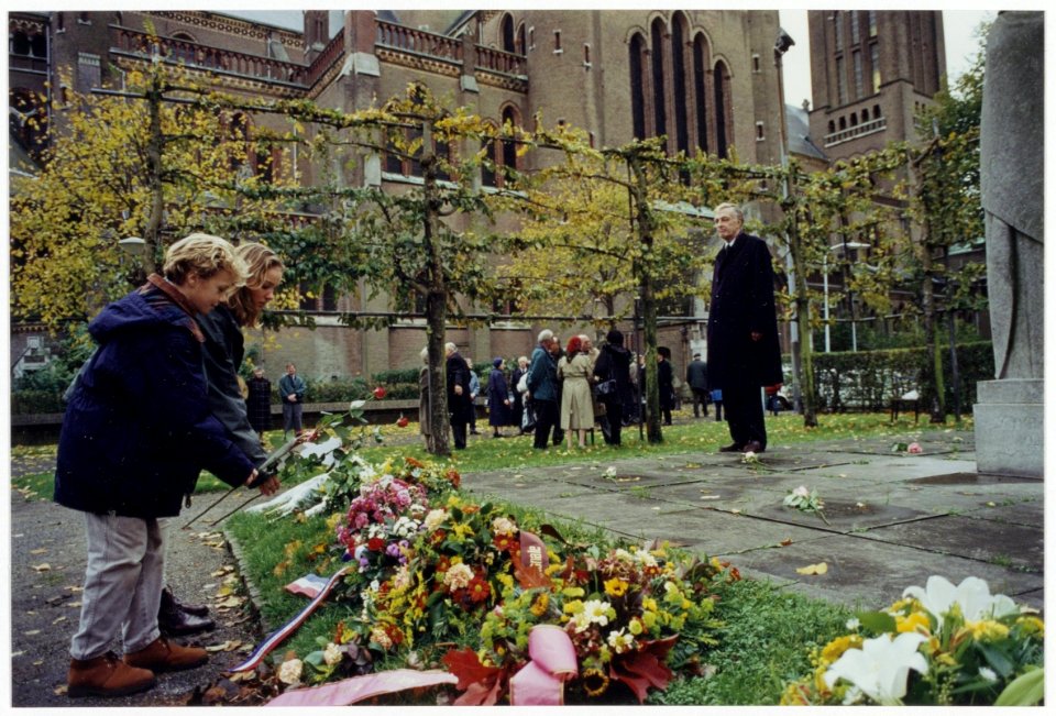 Leerlingen van de Bavoschool leggen een krans bij het verzetsmonument naast de Sint Bavo Kathedraal, ter herdenking van de tien mannen die op 26 oktober 1944 werden geëxcecuteerd als vergeld, NL-HlmNHA 54035233