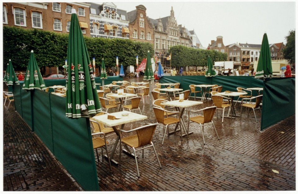Leeg terras op de Grote Markt op een verregende dag, ziende naar het noordoosten. NL-HlmNHA 54036071