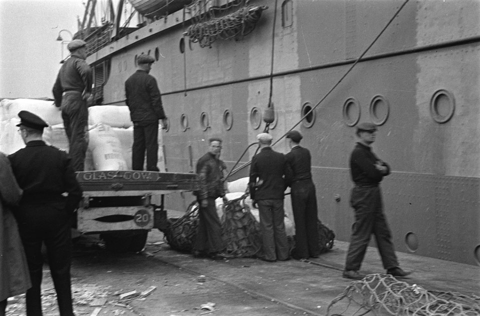 Lading wordt aan boord gebracht bij een Nederlands koopvaardijschip, Bestanddeelnr 935-2932