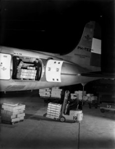 Luchthavenpersoneel bezig met laden of lossen van vracht van een DC-4 van KLM, Bestanddeelnr 190-0994
