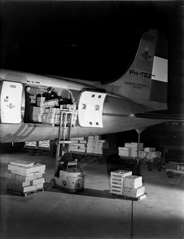 Luchthavenpersoneel bezig met laden of lossen van vracht van een DC-4 van KLM, Bestanddeelnr 190-0990