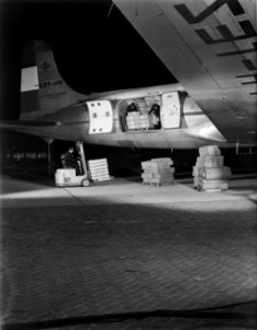 Luchthavenpersoneel bezig met laden of lossen van vracht van een DC-4 van KLM, Bestanddeelnr 190-0991