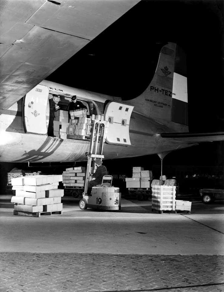 Luchthavenpersoneel bezig met laden of lossen van vracht van een DC-4 van KLM, Bestanddeelnr 190-0992