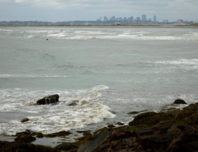 Lynn Massachusetts surfers riding waves with Boston in background photo