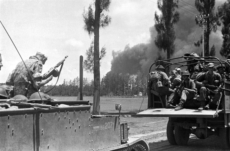 Links een soldaat met een tommy-gun op een brencarrier Voor hem een vrachtwagen, Bestanddeelnr 5735