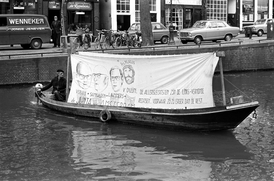 Man in een boot voor het Amsterdamse stadhuis met een spandoek gericht tegen de , Bestanddeelnr 927-9250