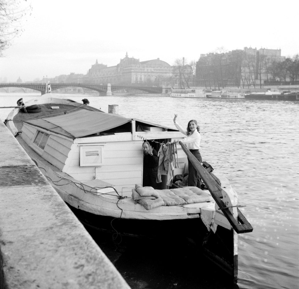 Man en vrouw zwaaiend in de kuip van een woonboot die is afgemeerd aan een kade , Bestanddeelnr 252-9394