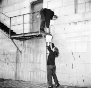 Man en vrouw bij het doorgeven van een emmer op de trappen langs de Seinekade in, Bestanddeelnr 252-9405