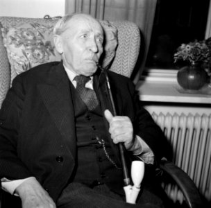 Man zit met een pijp in een stoel voor het raam te roken, Bestanddeelnr 252-9125