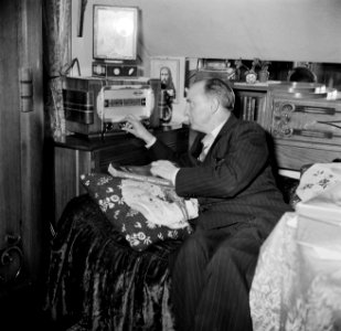 Man zittend op een bedbank terwijl hij de radio bedient, Bestanddeelnr 252-9334