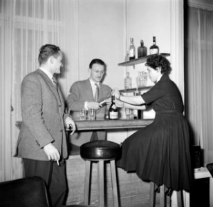 Man bereidt cocktails in zijn huisbar terwijl zijn vrouw een drankfles opent ee, Bestanddeelnr 252-9368