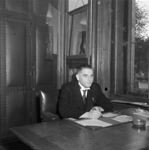 Man (in jacquet) zit achter bureau in werkkamer, Bestanddeelnr 900-8603
