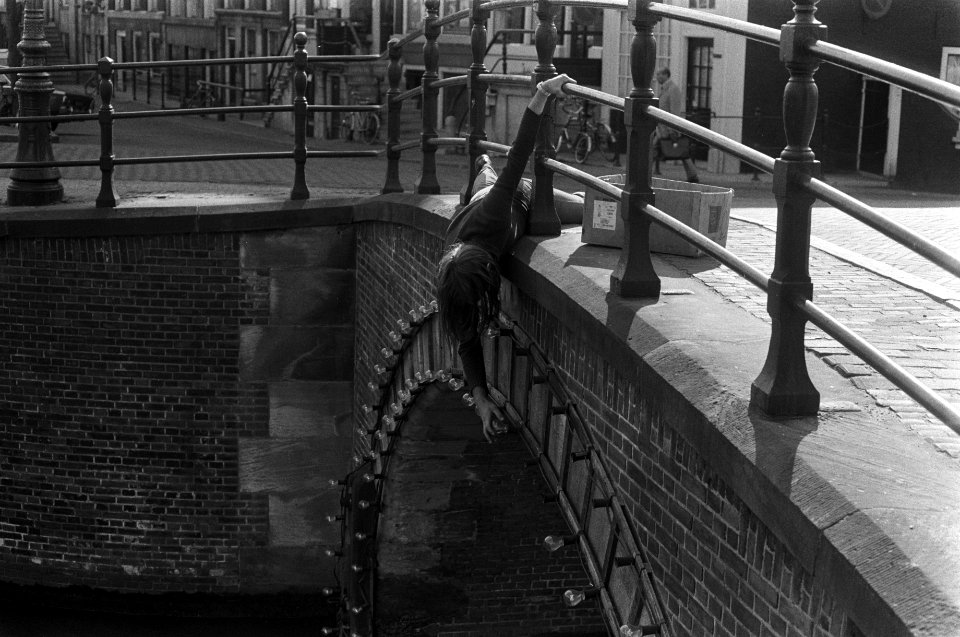 Man, liggend op brug draait lampjes in voor feestverlichting in Amsterdam, Bestanddeelnr 927-1518